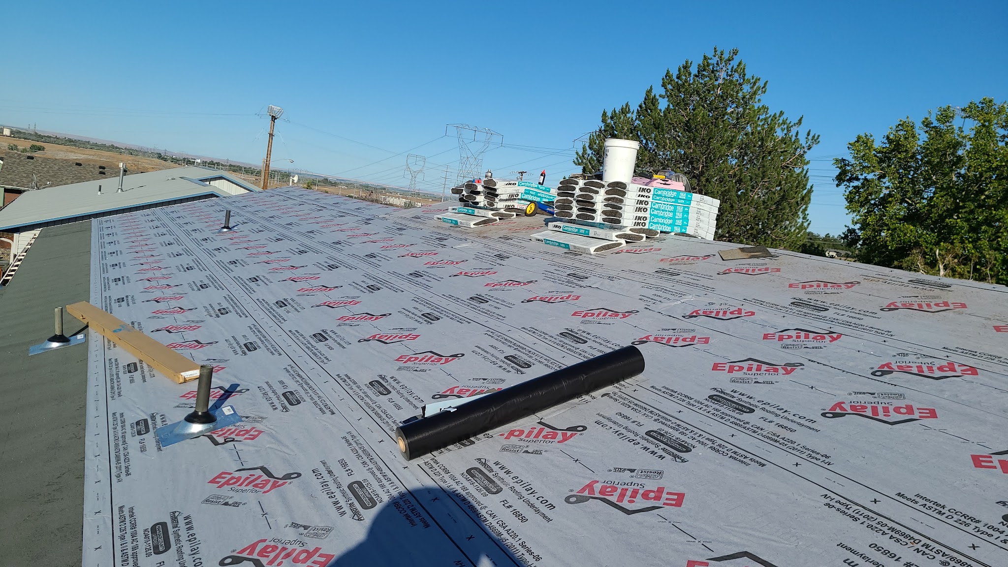 Aerial view of a gray shingle roof with vent stacks and boots installed