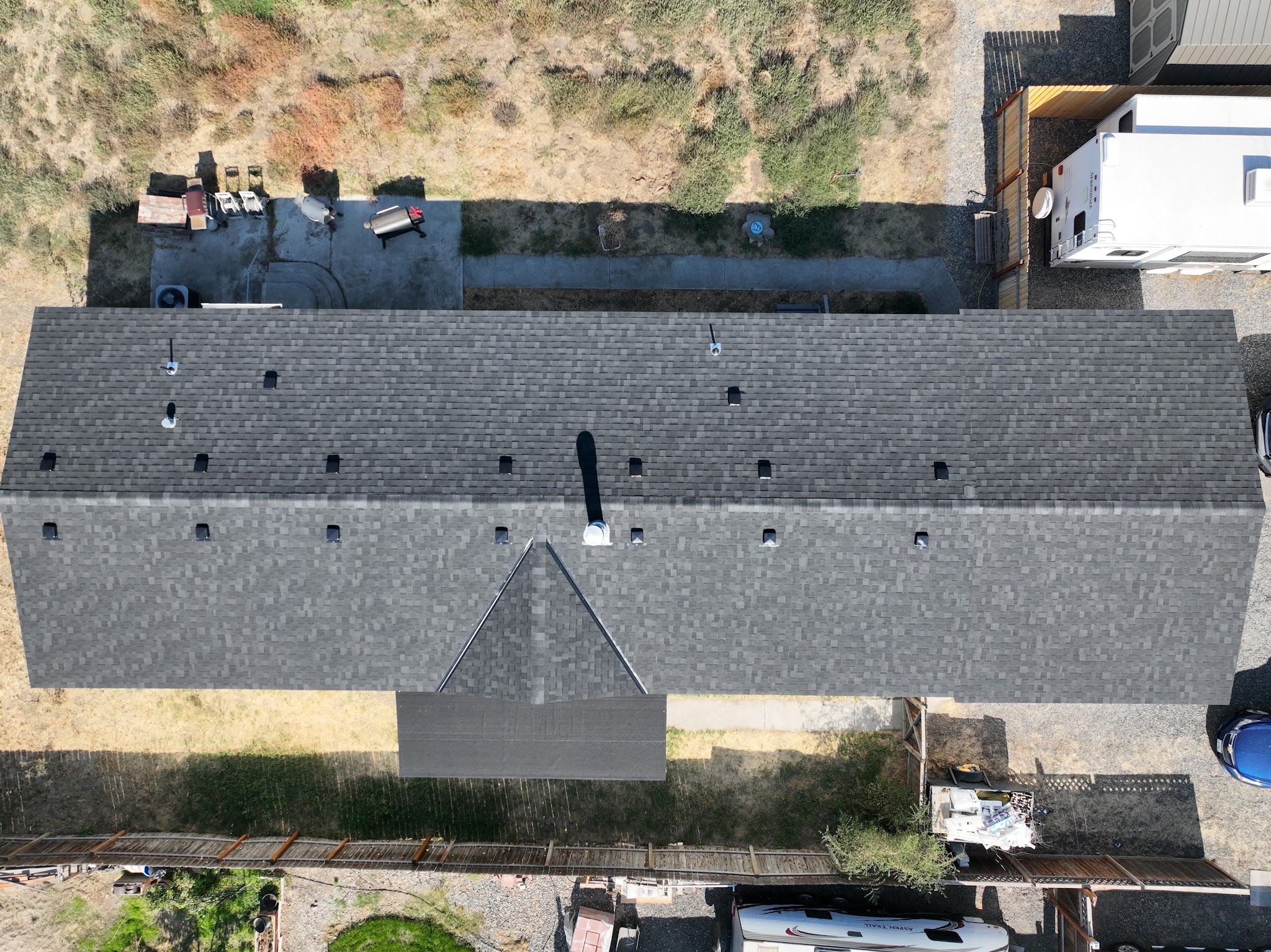 Aerial view of a finished shingle roof surrounded by mature trees